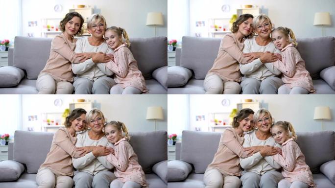 多世代女性拥抱在家庭沙发上微笑相机，家庭亲密