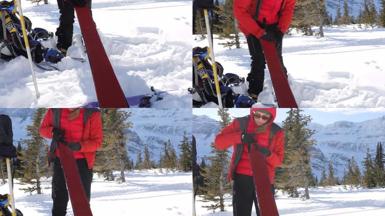 在山区环境中，女滑雪登山者将攀岩皮放在滑雪板上