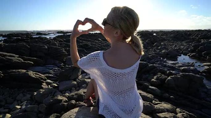 海滩上的年轻女子制作心形框架