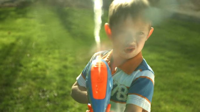 小男孩对着镜头喷水枪