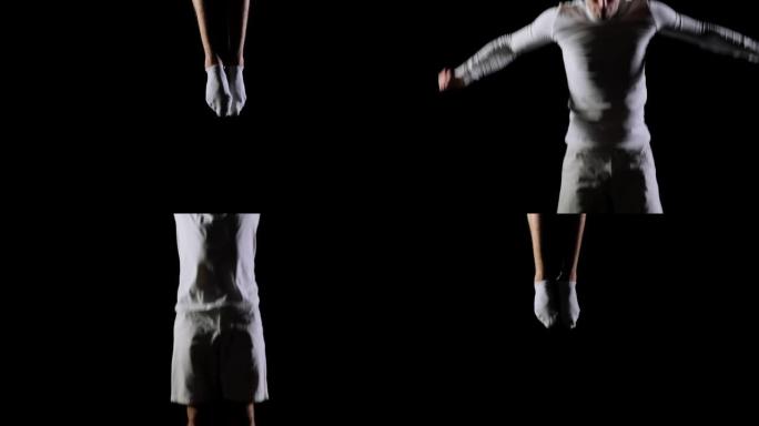 一位英俊的白色男性体操运动员在黑色背景上进行慢动作，旋转和翻转的杂技特技表演。飞行和自由的感觉