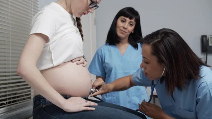 实习护士用听诊器听孕妇肚子