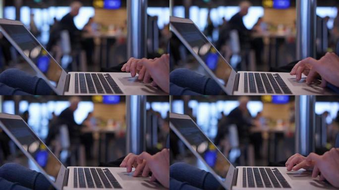 女性双手在笔记本电脑键盘上打字，女性在机场大厅工作，学习