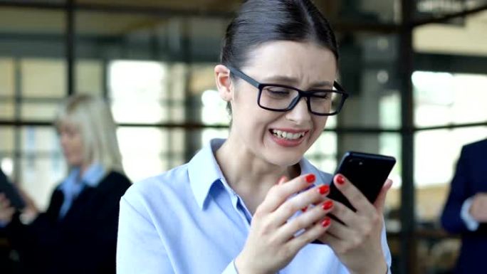 年轻的女经理表现出yes手势，在电话上阅读好消息