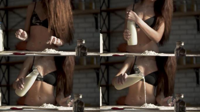 穿着黑色胸罩的女孩把面粉弄松，然后往里面倒牛奶。穿着内衣的女人正在厨房做饭。缓慢的运动。