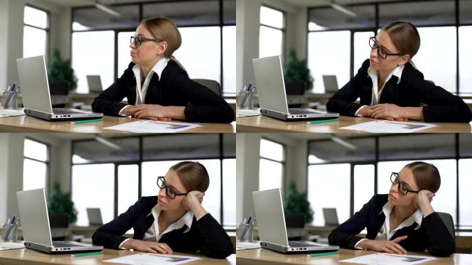 年轻女子无聊地在办公室的计算机上工作，精疲力尽且没有动力