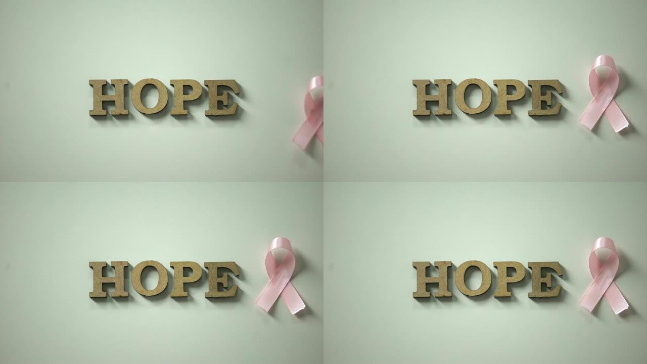 希望字和粉红丝带放在桌上，提高乳腺癌意识，保护健康