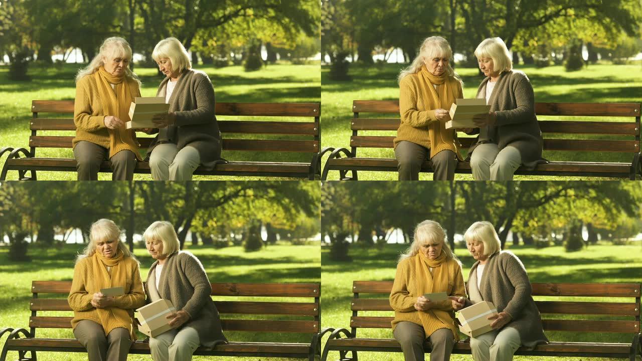 老太太在公园的长凳上看着已故朋友的照片，黄金岁月