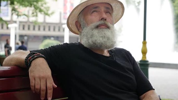 长胡子的老人坐在城市的长椅上
