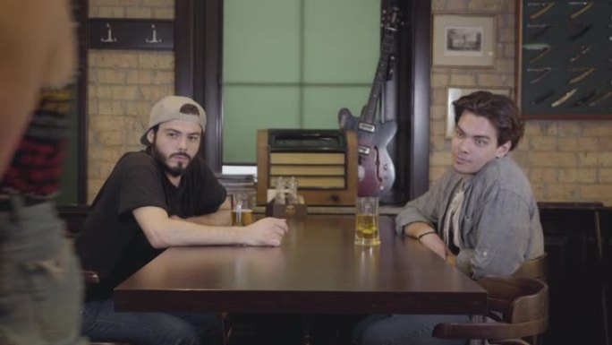 两个男人坐在酒吧里一起喝啤酒。