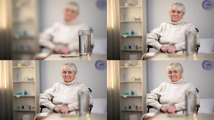 沮丧的老妇人坐在轮椅上看着药，诊断