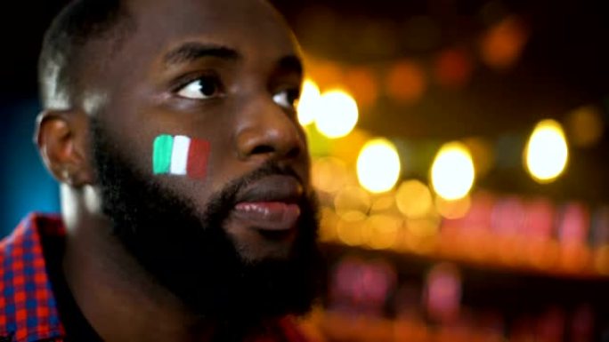 焦虑的黑色足球迷，脸颊上画着意大利国旗，使面部表情丢失