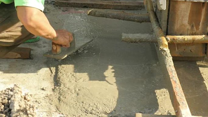 建筑工人在地板水泥上抹灰的手。