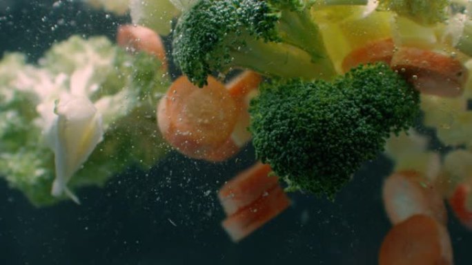 新鲜蔬菜以慢动作落在白色背景下的水下。沙拉，健康的食物，美味。饮食，素食生活方式，生态产品，有机。维