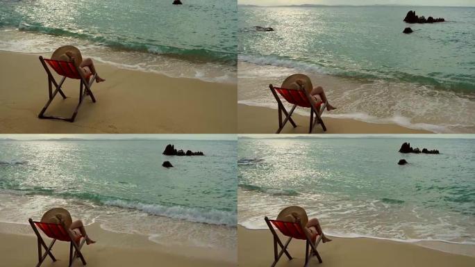 女人戴着帽子坐着她在沙滩海边舒适的椅子上开心，云和蓝天是无尽的背景