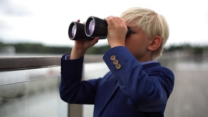 年轻的男生通过双筒望远镜在栏杆上寻找