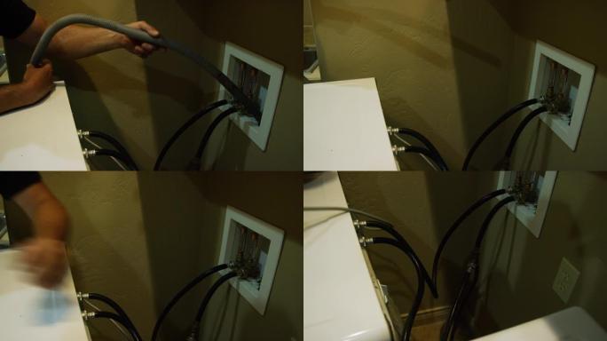 一名白人男子从洗衣机后面取下排水管，并从电源插座上拔下洗衣机的插头，以准备移动
