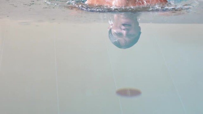 一个男人在游泳池里朝摄像机游泳的特写镜头