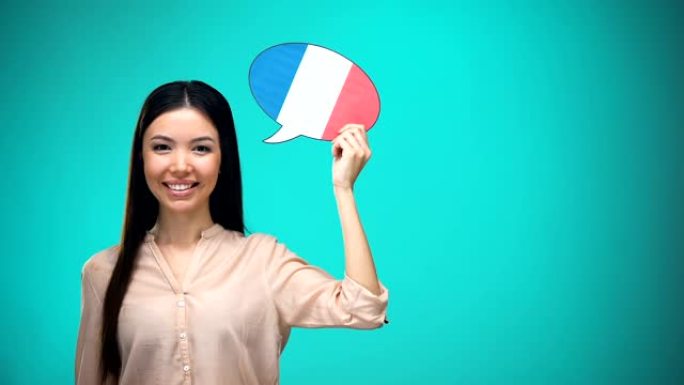 微笑的女孩拿着法国国旗演讲泡泡，学习语言，旅行理念