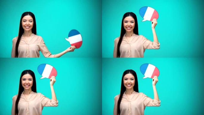 微笑的女孩拿着法国国旗演讲泡泡，学习语言，旅行理念