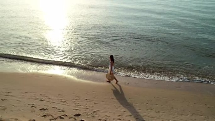 空中无人驾驶飞机拍摄，年轻女子在海滩边散步。