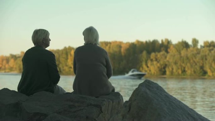成年女性在公园湖边聊天，享受周末户外休闲