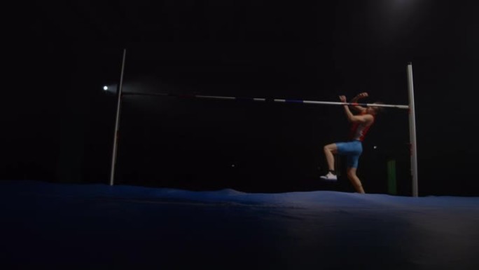 慢动作: 男性运动员在聚光灯下的黑暗背景上跳高