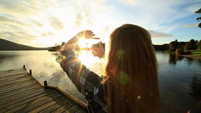 湖码头上的年轻女子在景观上做手指框