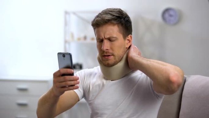 泡沫颈圈男子在手机上阅读信息，感到颈部疼痛