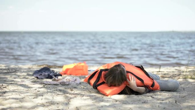 女人脱下救生衣咳嗽躺在沙滩上，沉船难民幸存者