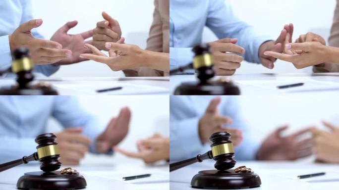 夫妻在法庭上争吵，桌上有订婚戒指的木槌，离婚概念