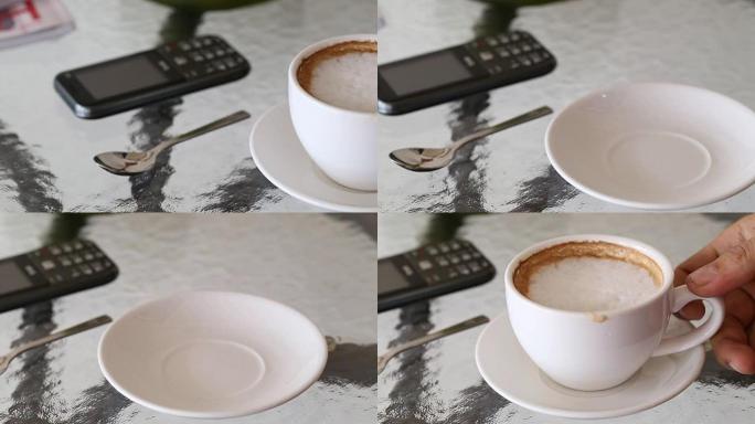 咖啡馆桌上的白咖啡杯和男人的手拿起喝酒。