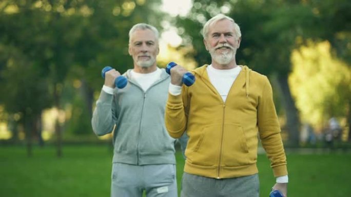 老人在公园里举起哑铃，朋友一起锻炼，健身