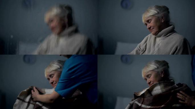 医务人员在下雨的夜晚用毯子盖住了熟睡的老妇人，护理