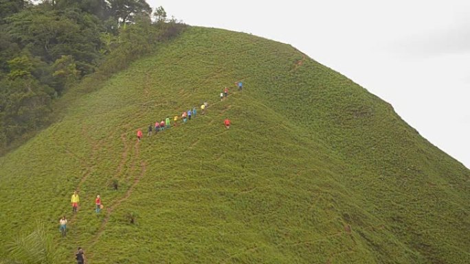 一群旅行者在雨天走在草山上