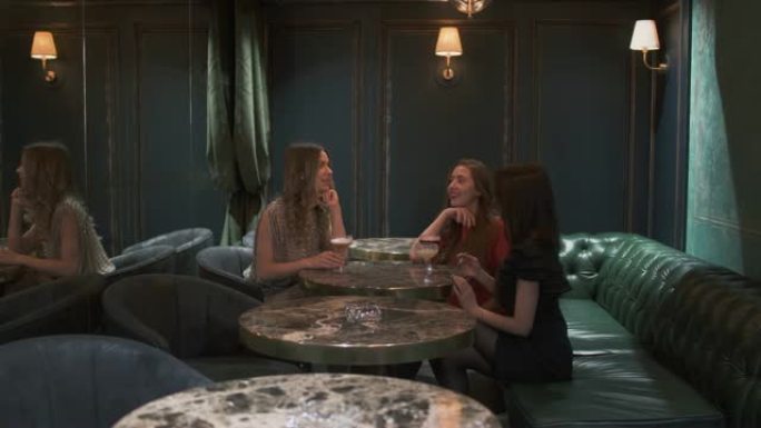 三个开朗的女人坐在咖啡馆的小桌子旁聊天。