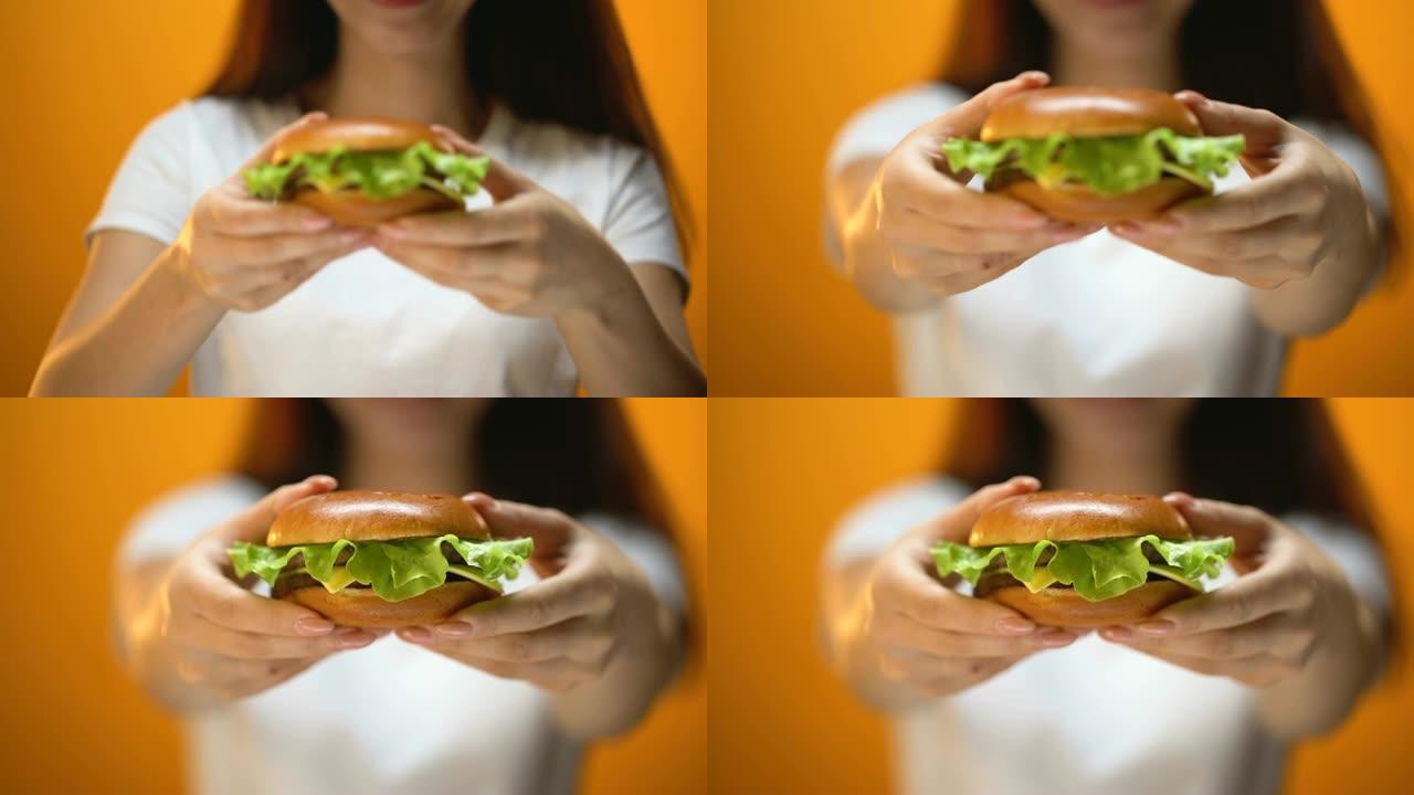女孩向镜头展示牛肉汉堡，快餐诱惑，不健康饮食