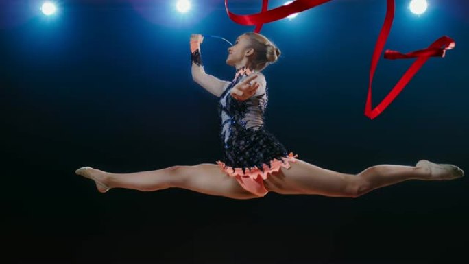 SLO MO艺术体操运动员的红丝带在空中旋转，进行了一次跳跃
