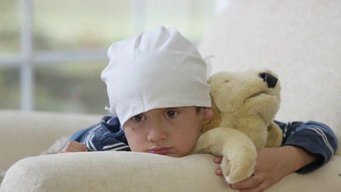 患有癌症的小男孩抱着玩偶趴着发呆可怜小朋