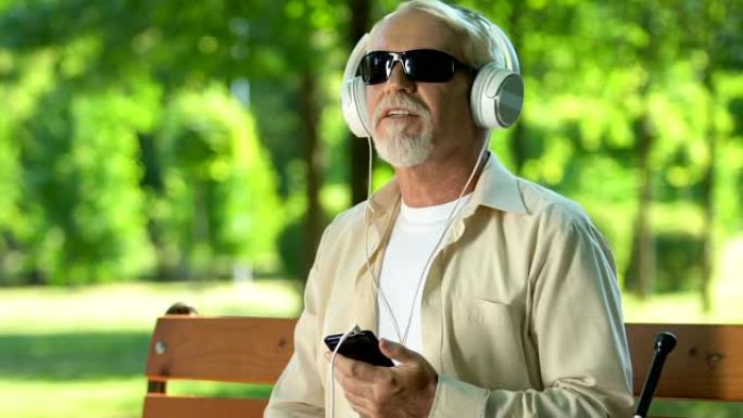 患有视觉障碍的高级男子喜欢，戴着耳机听音乐