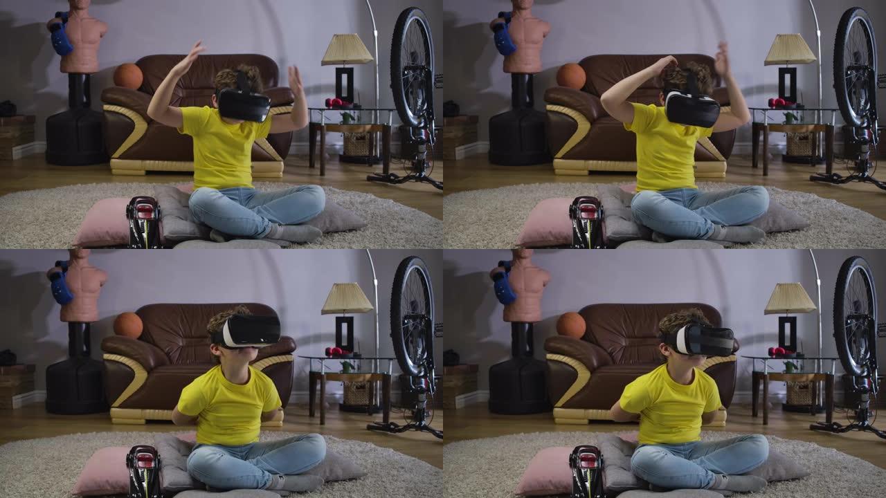 年轻的高加索卷发男孩在戴着VR谷歌和说话时在情感上打手势。穿着黄色t恤和蓝色牛仔裤的漂亮男生使用3d