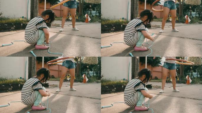 小女孩和她的母亲跳绳玩呼啦圈