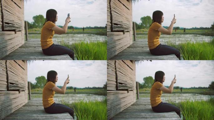 迷人的女性在稻田用智能手机拍照