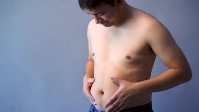 胖子超重，手握肥胖的腹部，在孤立的背景上，灰色的背景颜色。