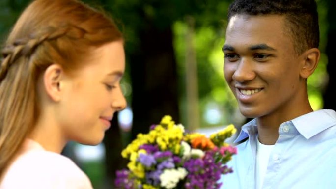 男性青少年在公园给可爱的女孩送花，爱的宣言，魔法时刻