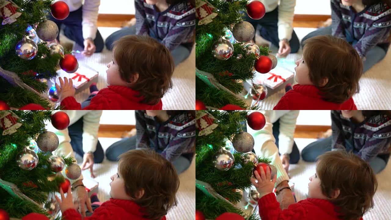 可爱的女婴玩树上的圣诞装饰品和坐在她面前的面目全非的父母的背景图