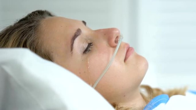 悲伤哭泣的女人用鼻插管躺在医院的病床上，疾病绝望