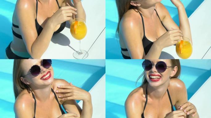 穿着时尚太阳镜和比基尼的微笑开朗女士在游泳池里喝鸡尾酒