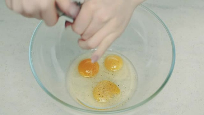女人在碗中的蛋黄上撒黑胡椒
