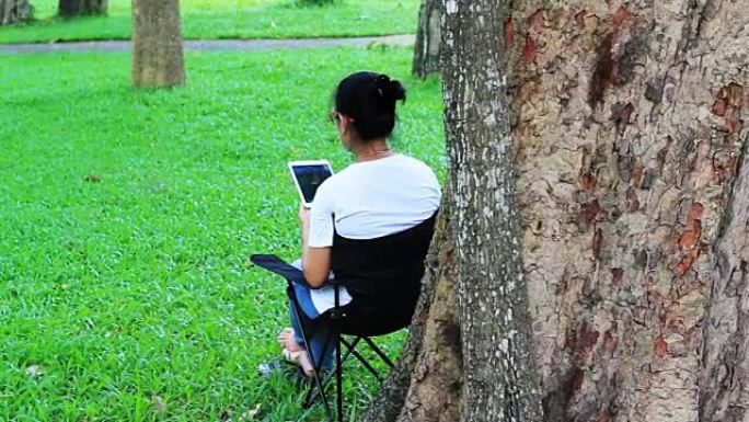 亚洲女性使用数字设备在泰国清迈府公园进行股市交易